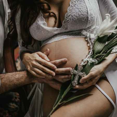 man s hand on pregnant woman s belly